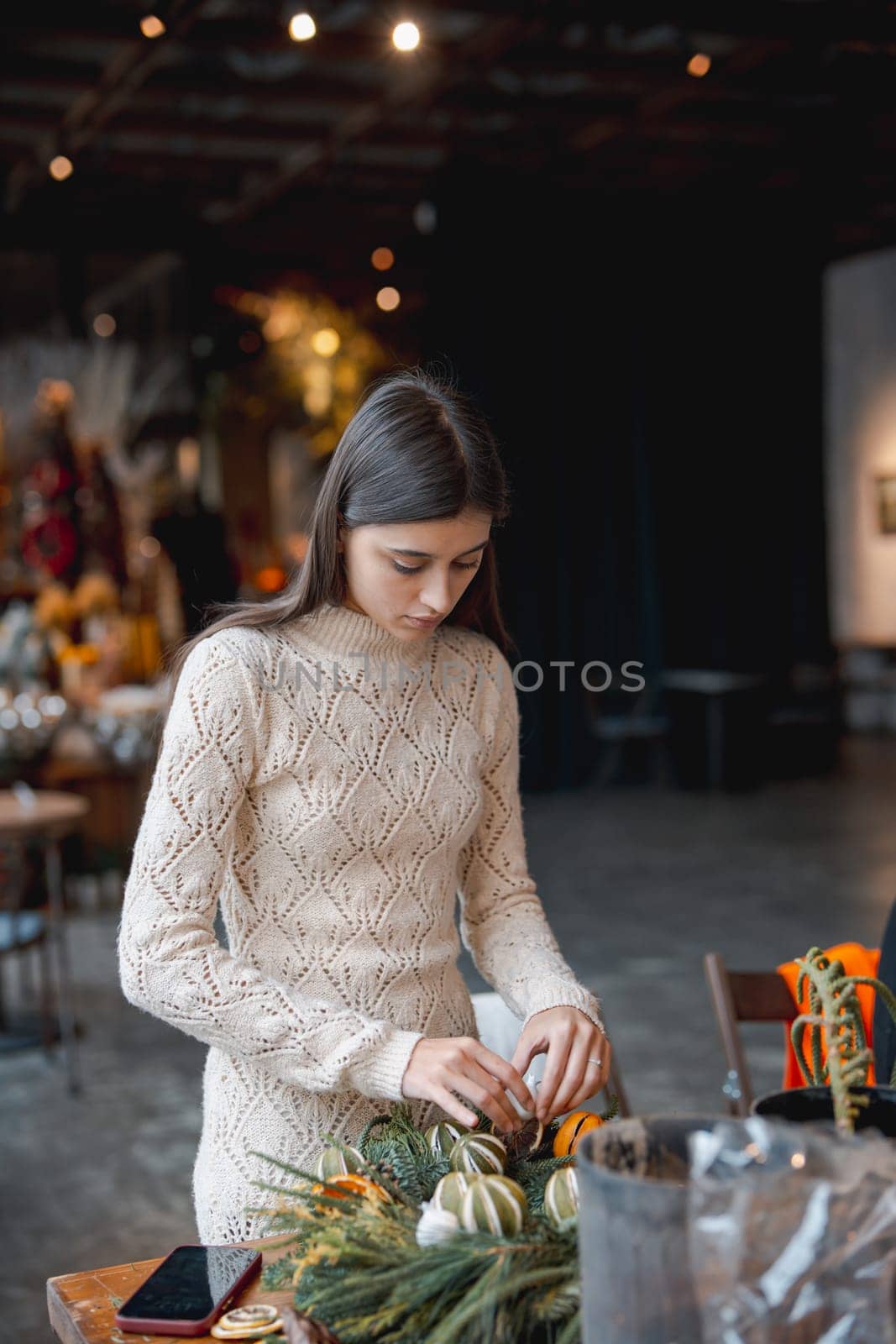 A radiant young woman fully immersed in a Christmas decor DIY workshop. High quality photo