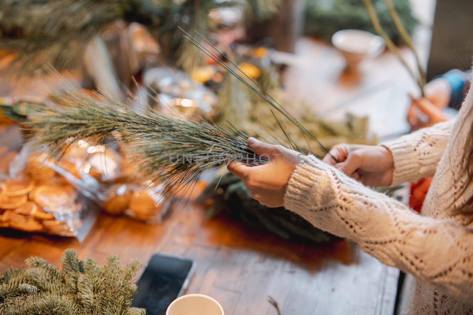 A young girl crafting a Christmas wreath during a decor-making masterclass. High quality photo