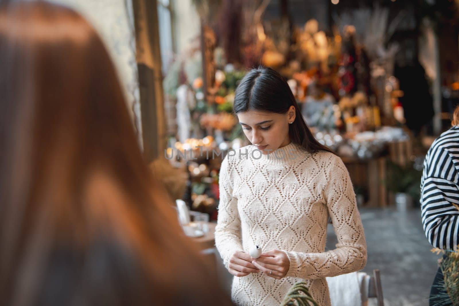 A young lady making a holiday wreath during a crafting class. by teksomolika