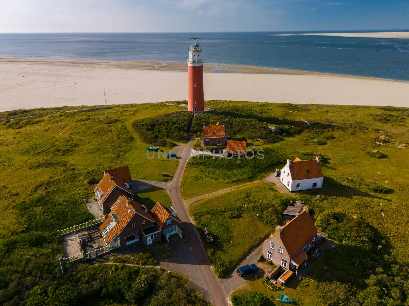 An awe-inspiring aerial view of a majestic lighthouse standing tall amidst the sandy shores of Texel, Netherlands.