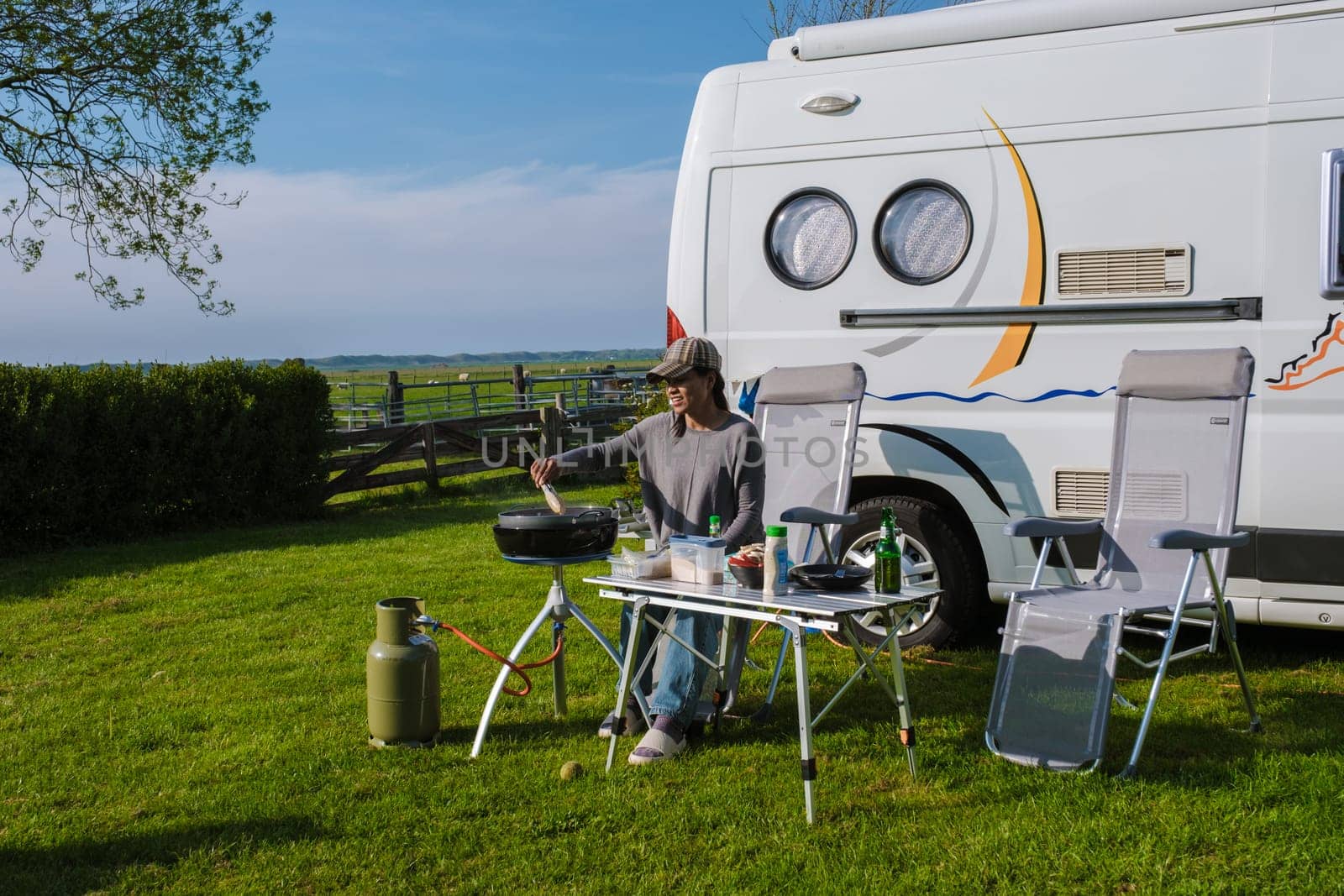 A woman sits quietly at a table, with an RV in the background. The scene exudes a sense of peace and anticipation for the journey ahead by fokkebok