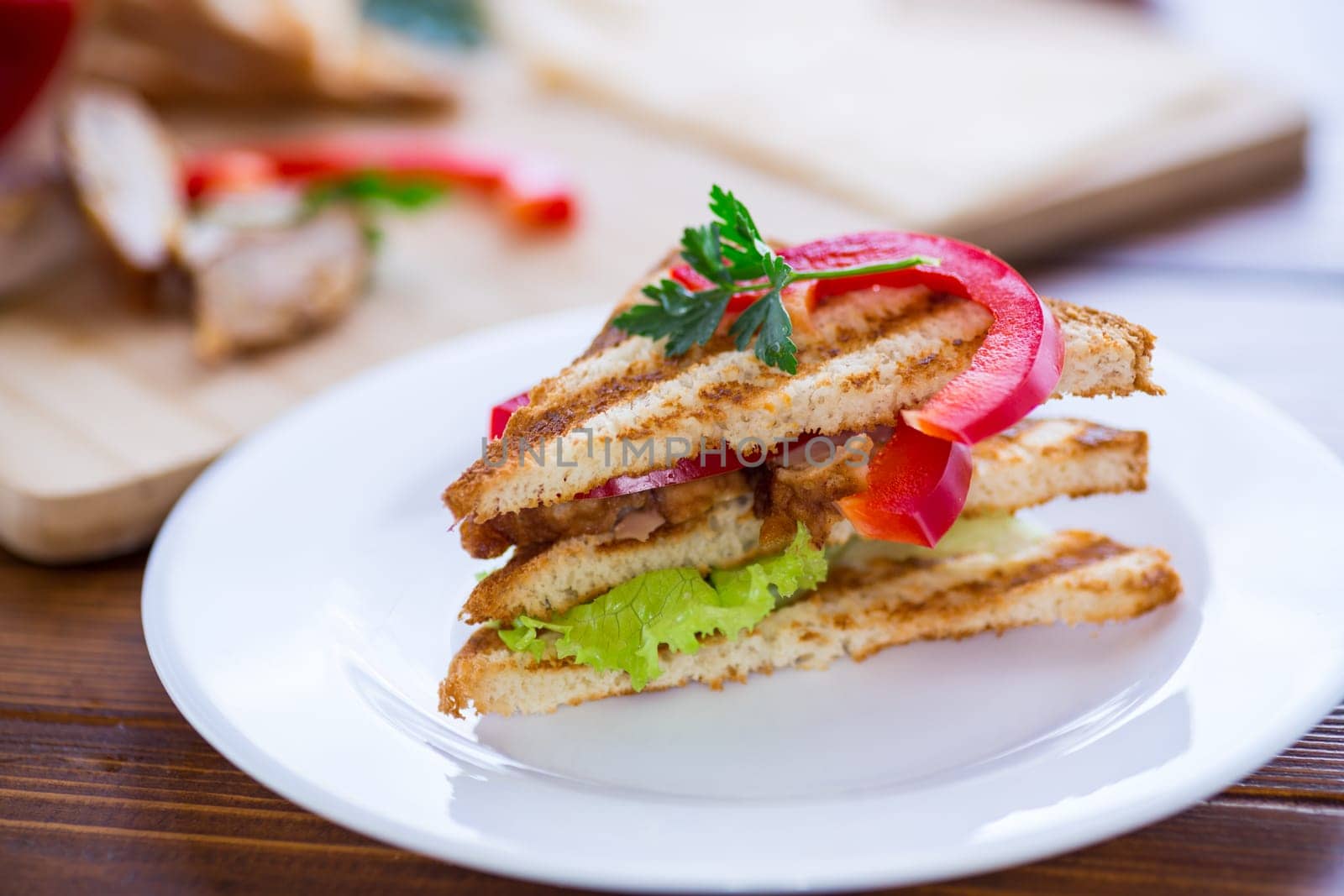 fried toast with chicken, salad, greens on a wooden table .