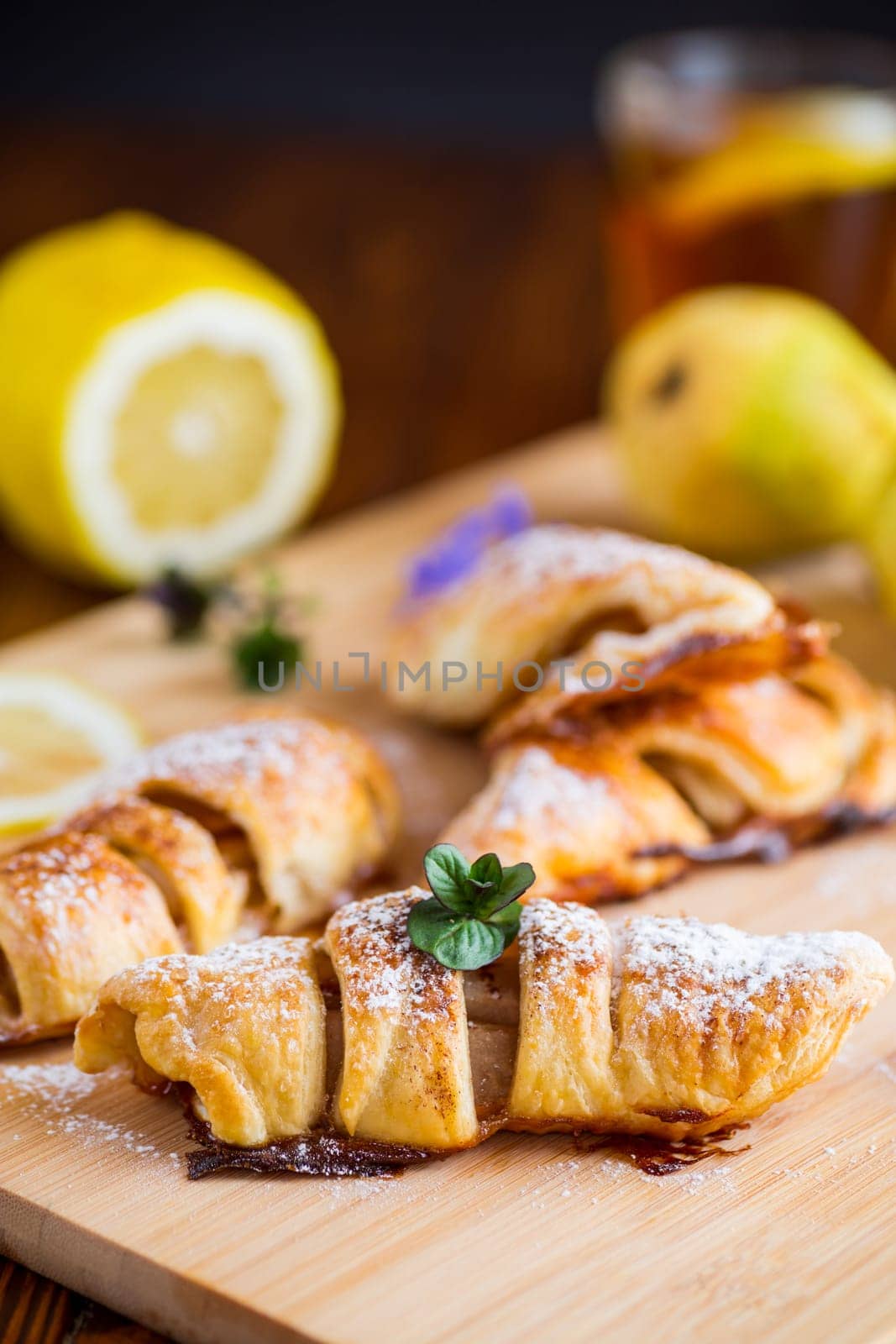 Sweet pastries, puff pastries with pears, on a wooden table by Rawlik