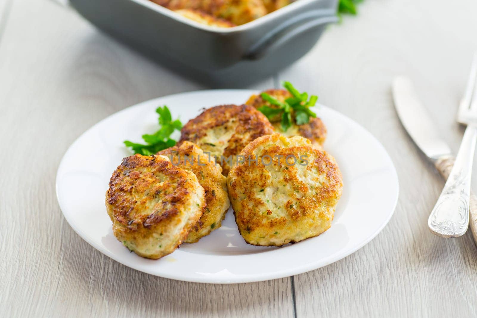 fried meat cutlets in a ceramic form on a wooden table by Rawlik