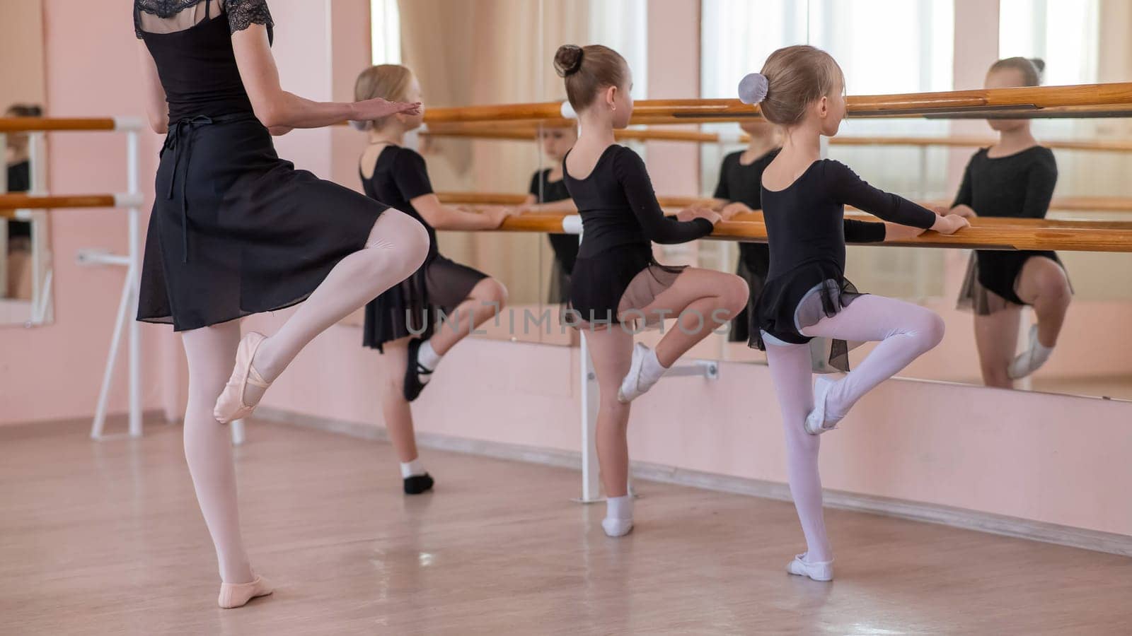 Caucasian woman teaches little girls ballet at the barre. by mrwed54
