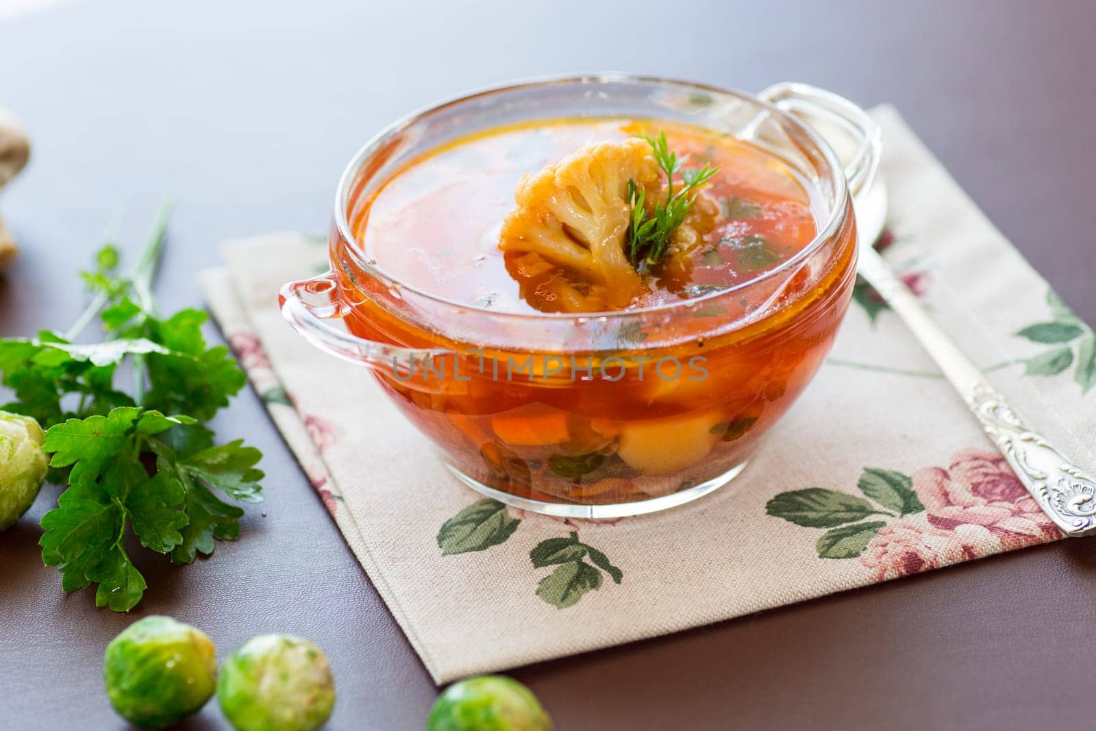 vegetable soup with Brussels sprouts and cauliflower, in a glass plate on a wooden table by Rawlik