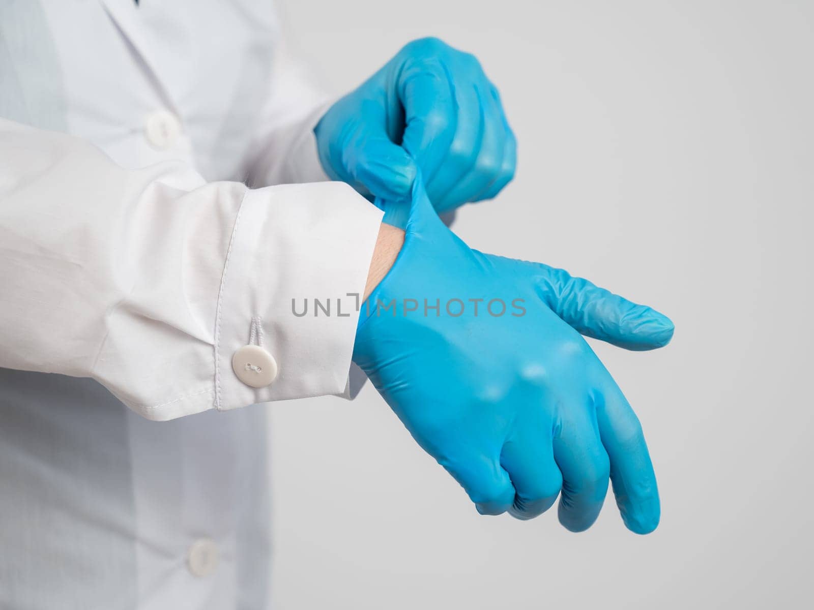 The doctor puts on latex gloves on a white background