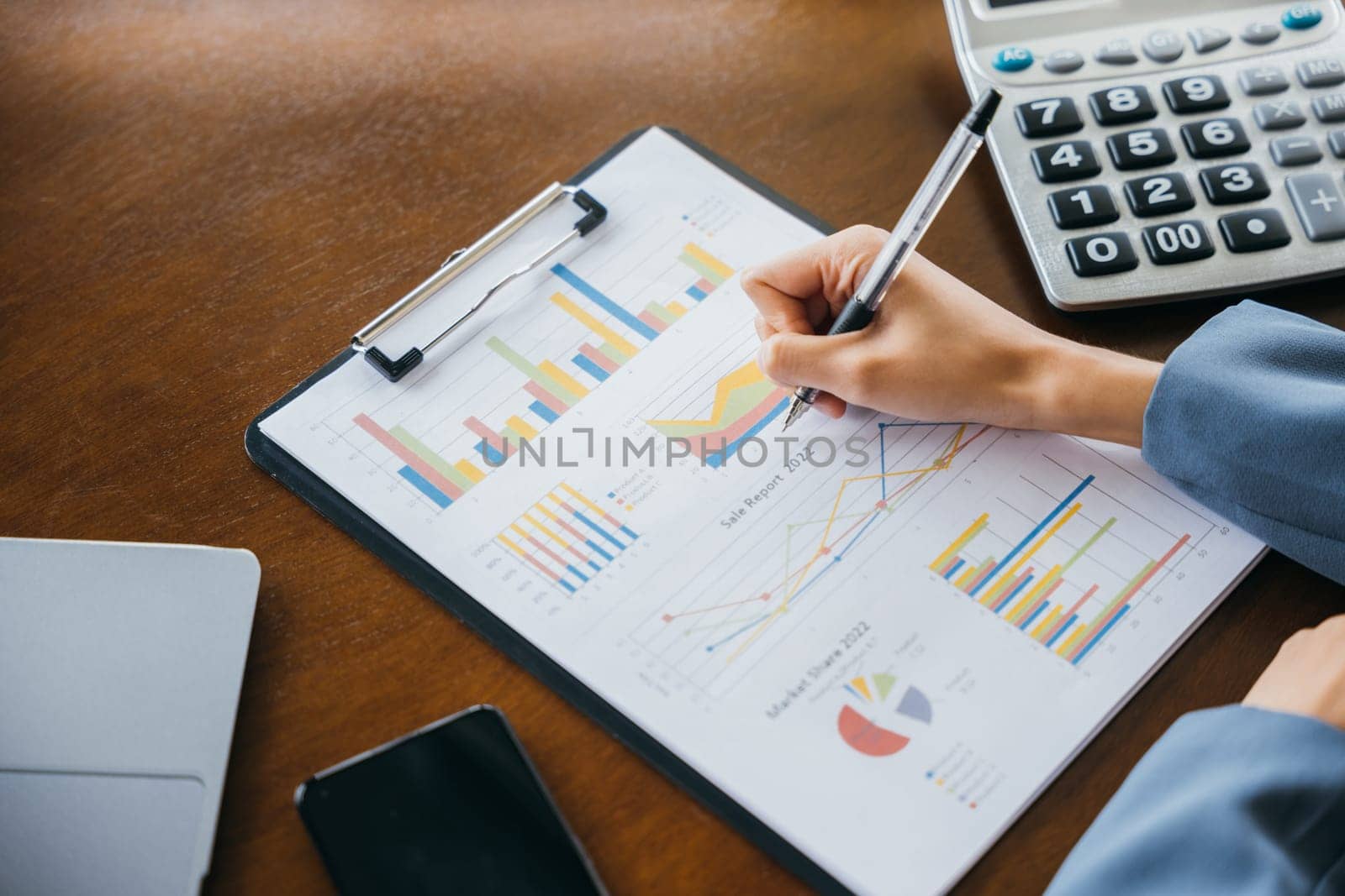 Business woman writing marketing note on paper charts graphs by Sorapop