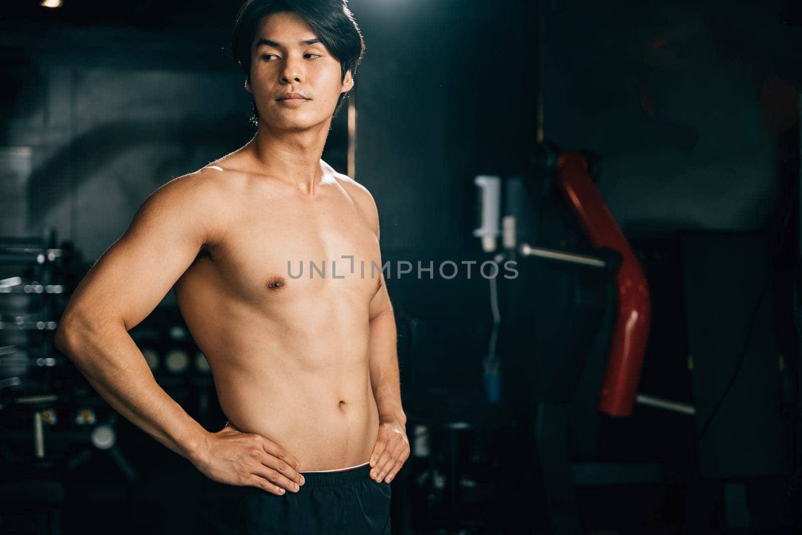 A handsome man with a toned body, standing confidently in his underwear, smiles for the camera, his bicep muscles flexed, showing his dedication to fitness. Healthy fitness Lifestyle with copy space
