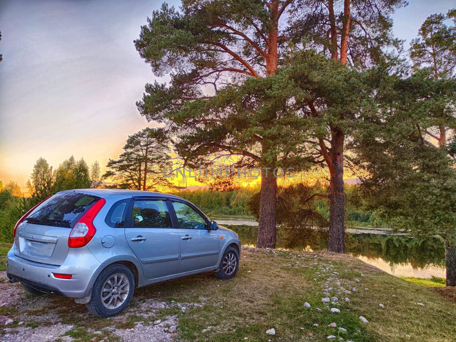 Twilight Road Trip Break in Forested Area. Car parked beside lake during a sunset break in the forest