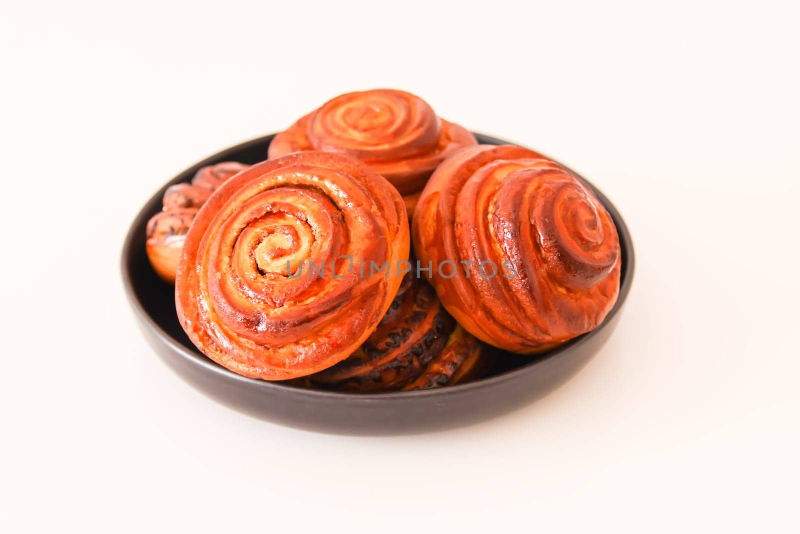 Sweet homemade cinnamon buns on a black ceramic plate.