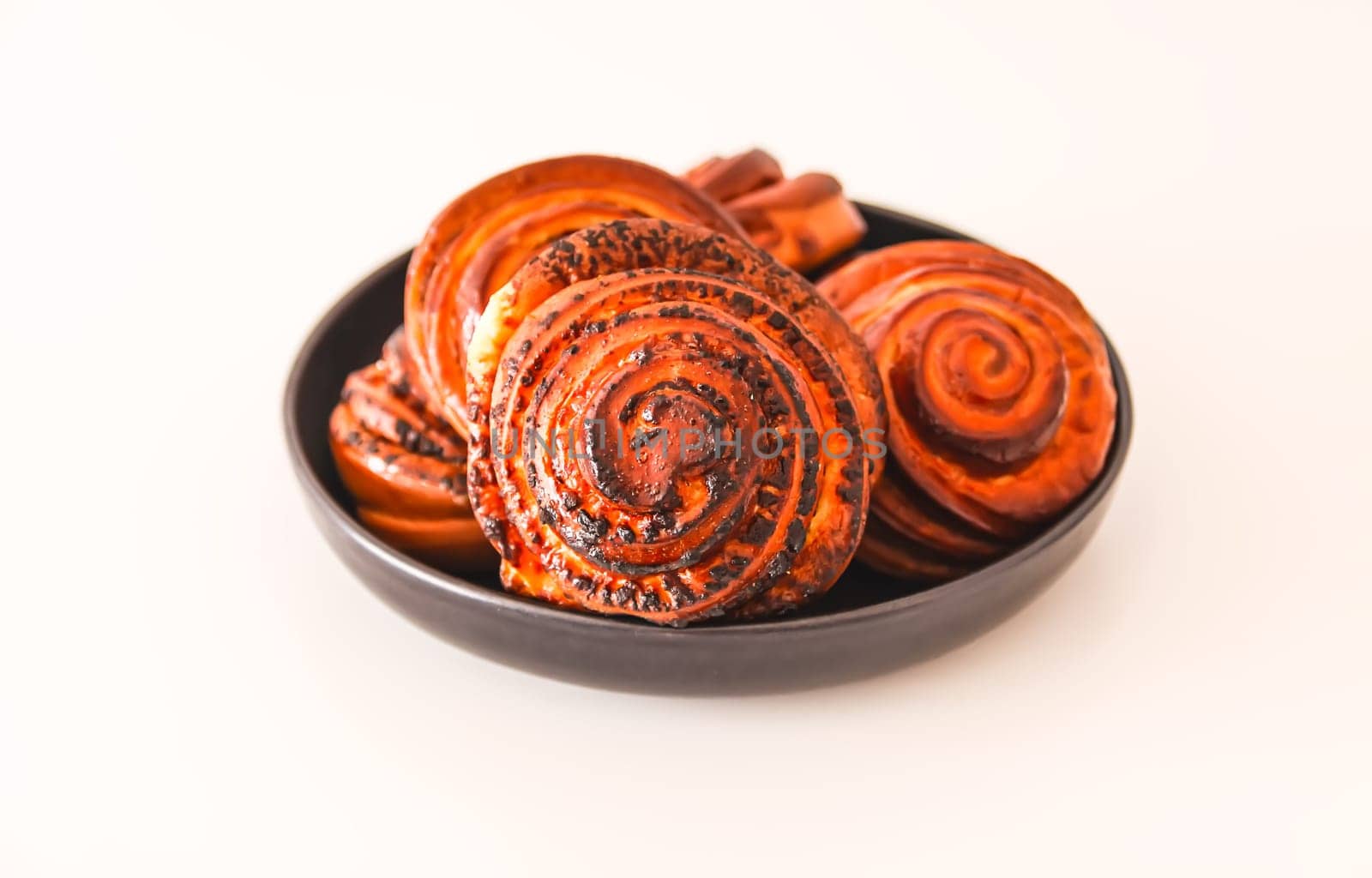 Sweet homemade cinnamon buns on a black ceramic plate.