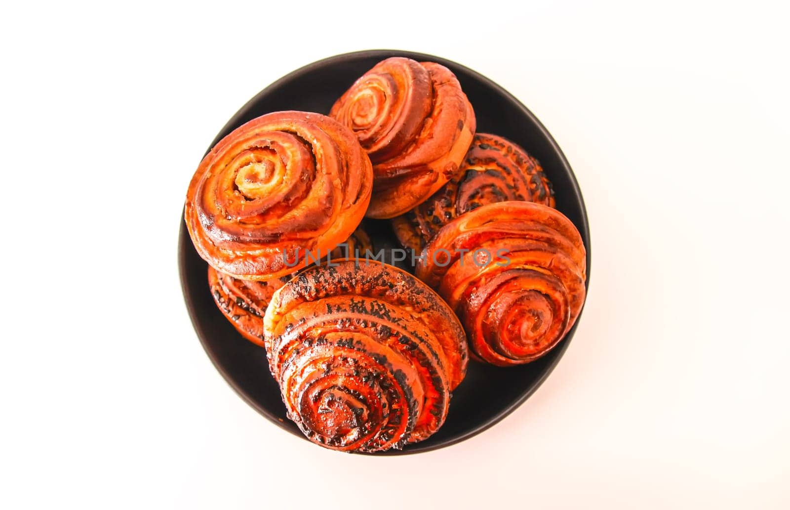 Sweet homemade cinnamon buns on a black ceramic plate.