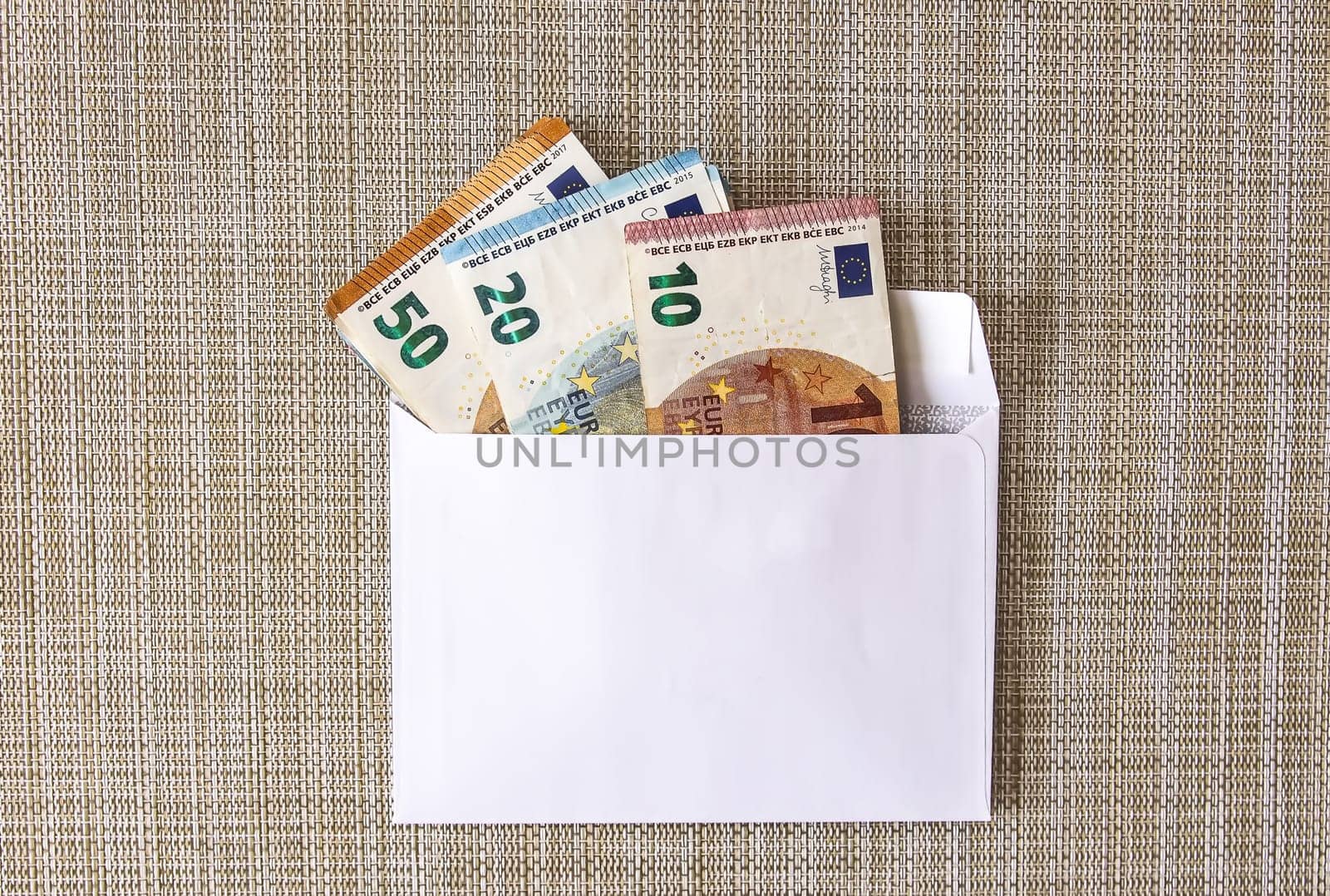 Euro money banknotes in the white paper envelope on a light background close up.