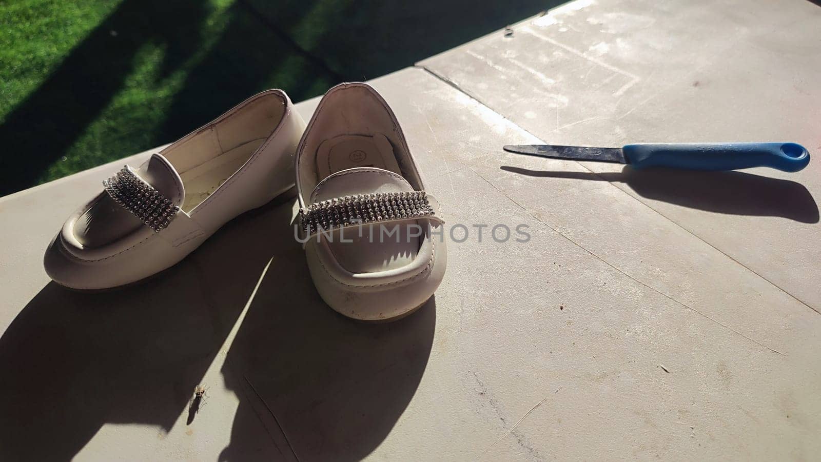women's white summer slippers shoes, knife on the street in the evening, objects. High quality photo
