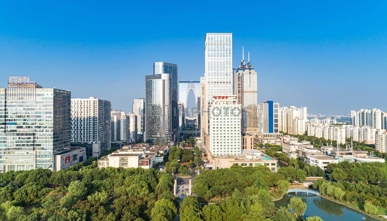 Suzhou, China - August 17, 2020: Aerial view of modern glass skyscrapers exterior with sunshine and reflection on the windows. Aerial over modern business office buildings, skyscrapers, financial district. by Busker