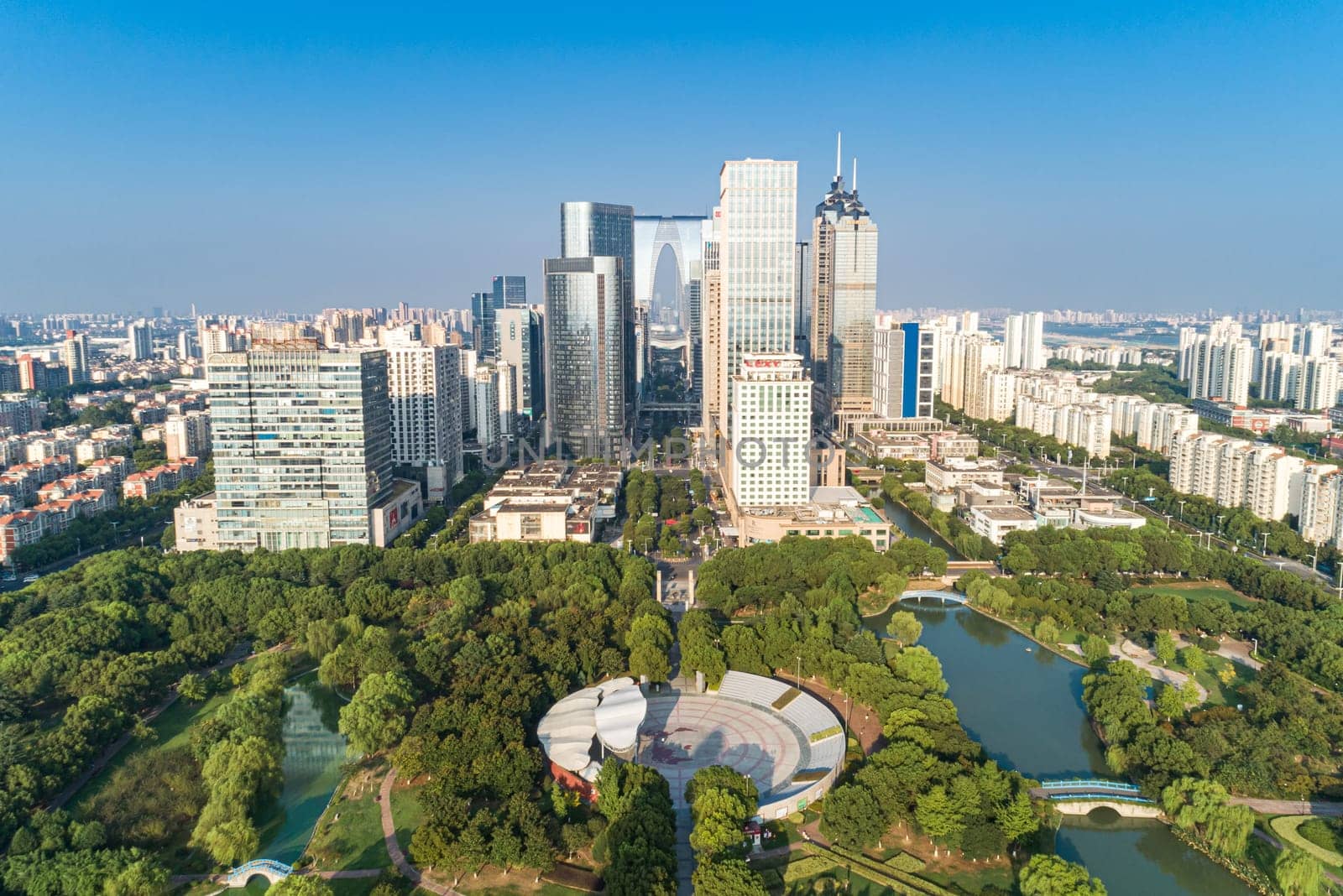 Suzhou, China - August 17, 2020: Aerial view of modern glass skyscrapers exterior with sunshine and reflection on the windows. Aerial over modern business office buildings, skyscrapers, financial district. by Busker