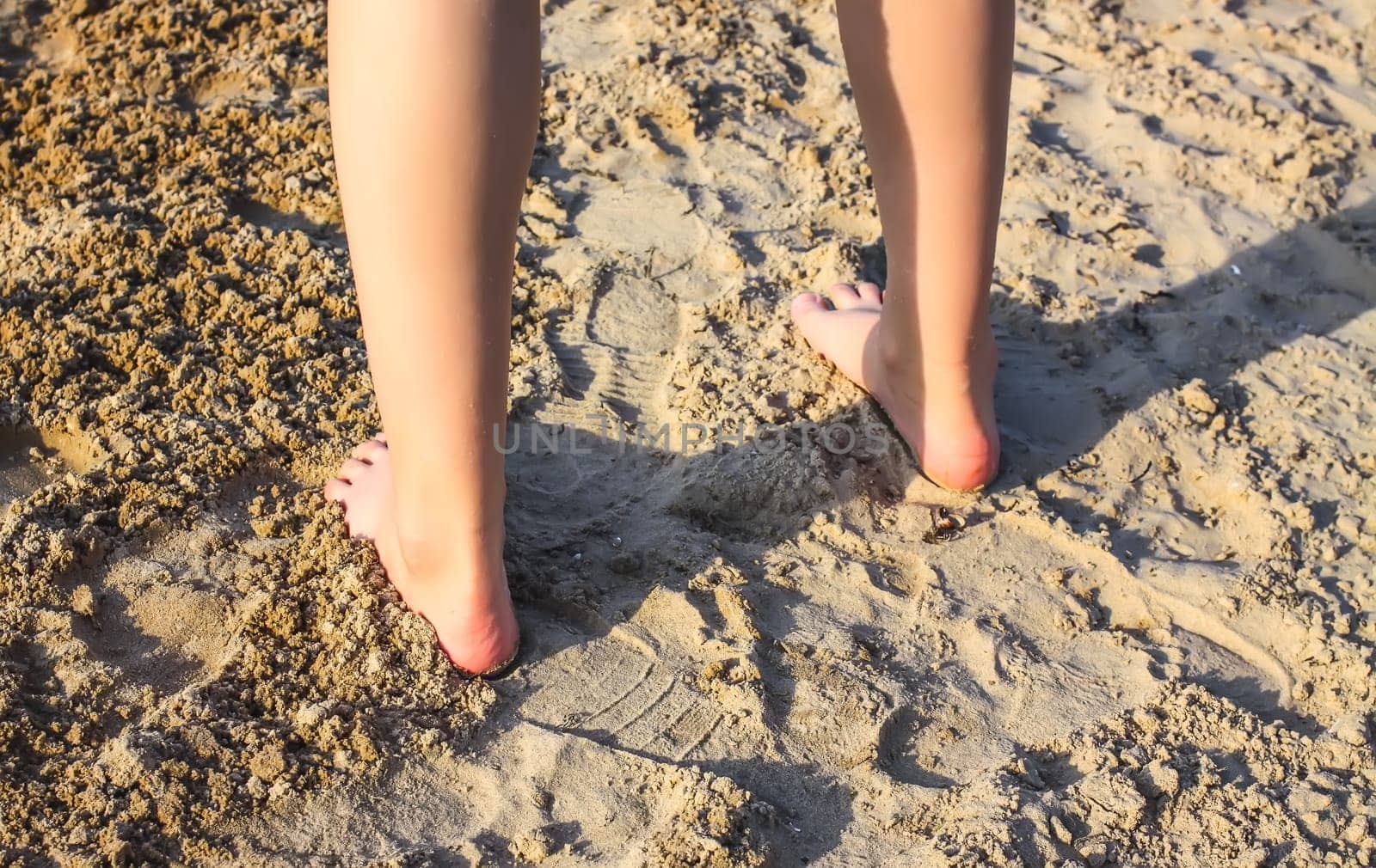 Child's bare feet walking at a beach.