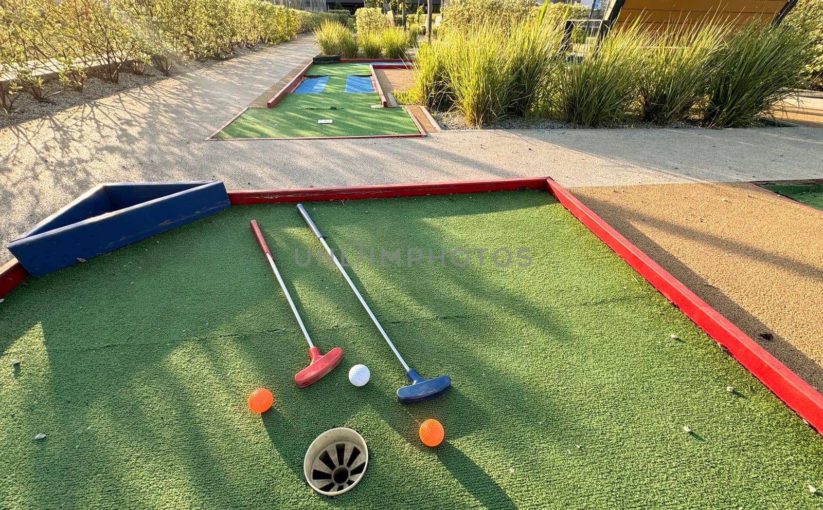 Assorted miniature golf putters and balls askew on synthetic grass. High quality photo