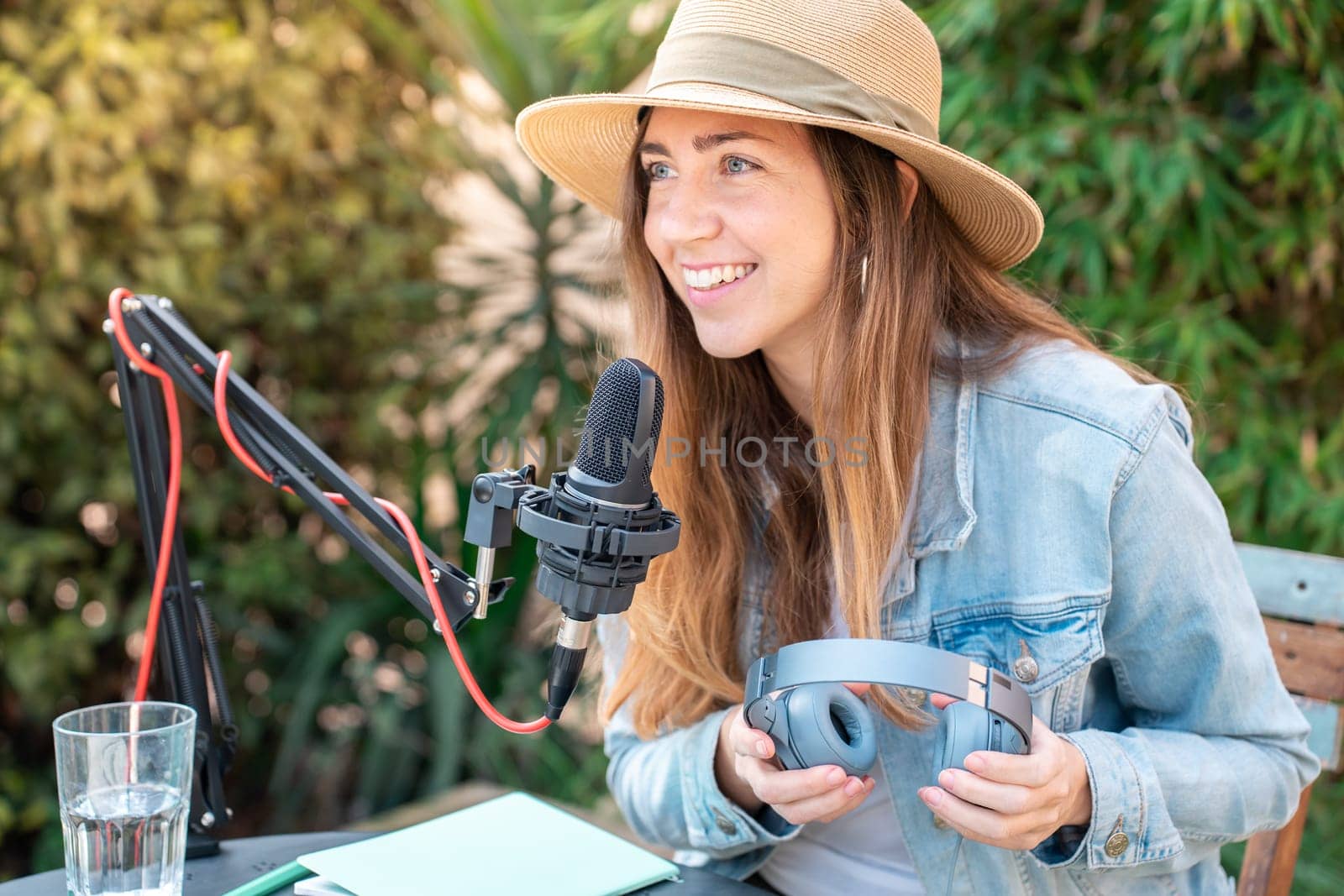 Attractive woman recording radio podcast - Young girl talking during live stream session outdoor. High quality photo