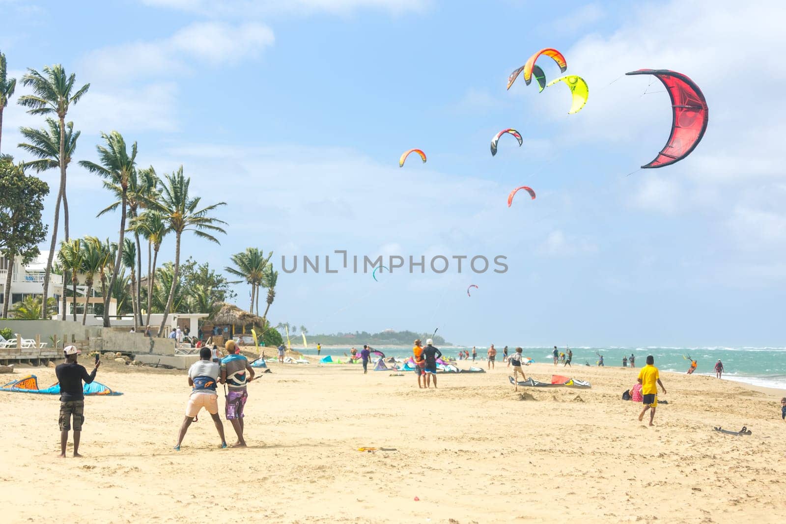 Crowd of active sporty people enjoying kitesurfing holidays and activities on perfect sunny day on Cabarete tropical sandy beach in Dominican Republic. by kasto