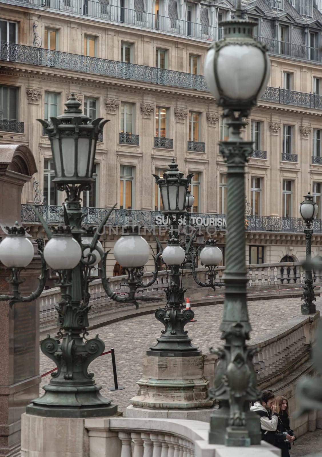 France, Paris - Jan 04, 2024 - Vintage lamp posts on with white handrail with the historic building in background at The opera house Palais Garnier. Architectural details of The Palais Garnier (Opera National de Paris). Place de l'Opéra (Opera Garnier) is famous Neo-baroque building in Paris, UNESCO World Heritage Site, Copy space, Selective focus.