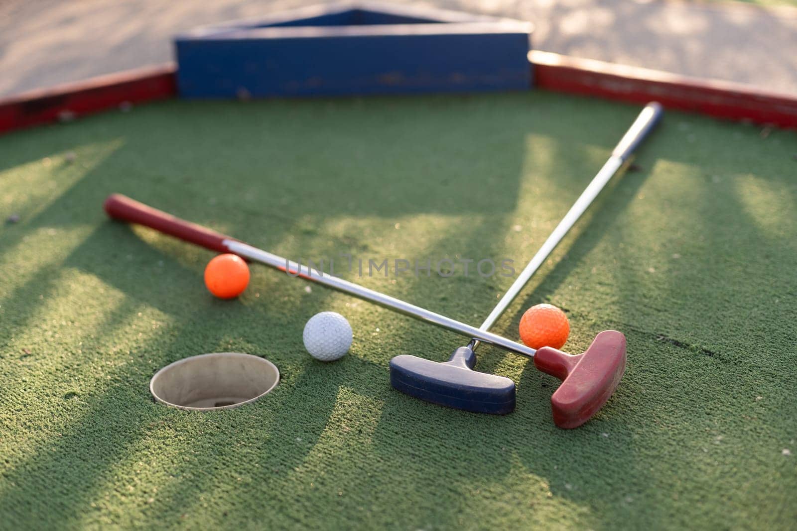 Assorted miniature golf putters and balls askew on synthetic grass. High quality photo