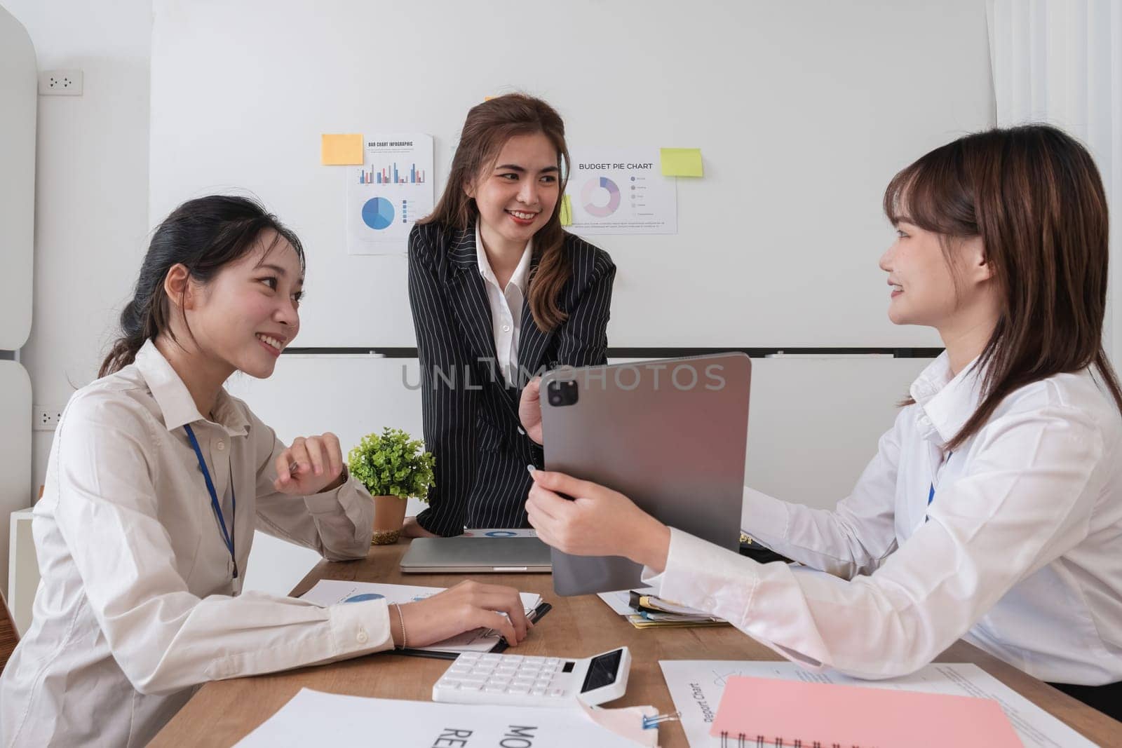 A group of Asian businesswomen in a conference room are discussing ways of working and improving their work. by wichayada