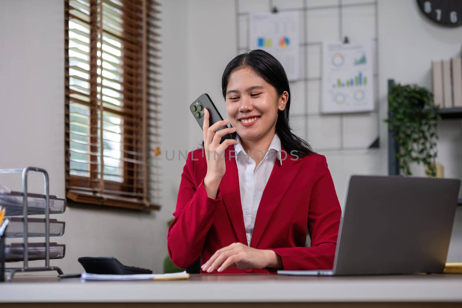 Beautiful accountant talking on the phone and calculating financial figures and calculating taxes for the company. by wichayada