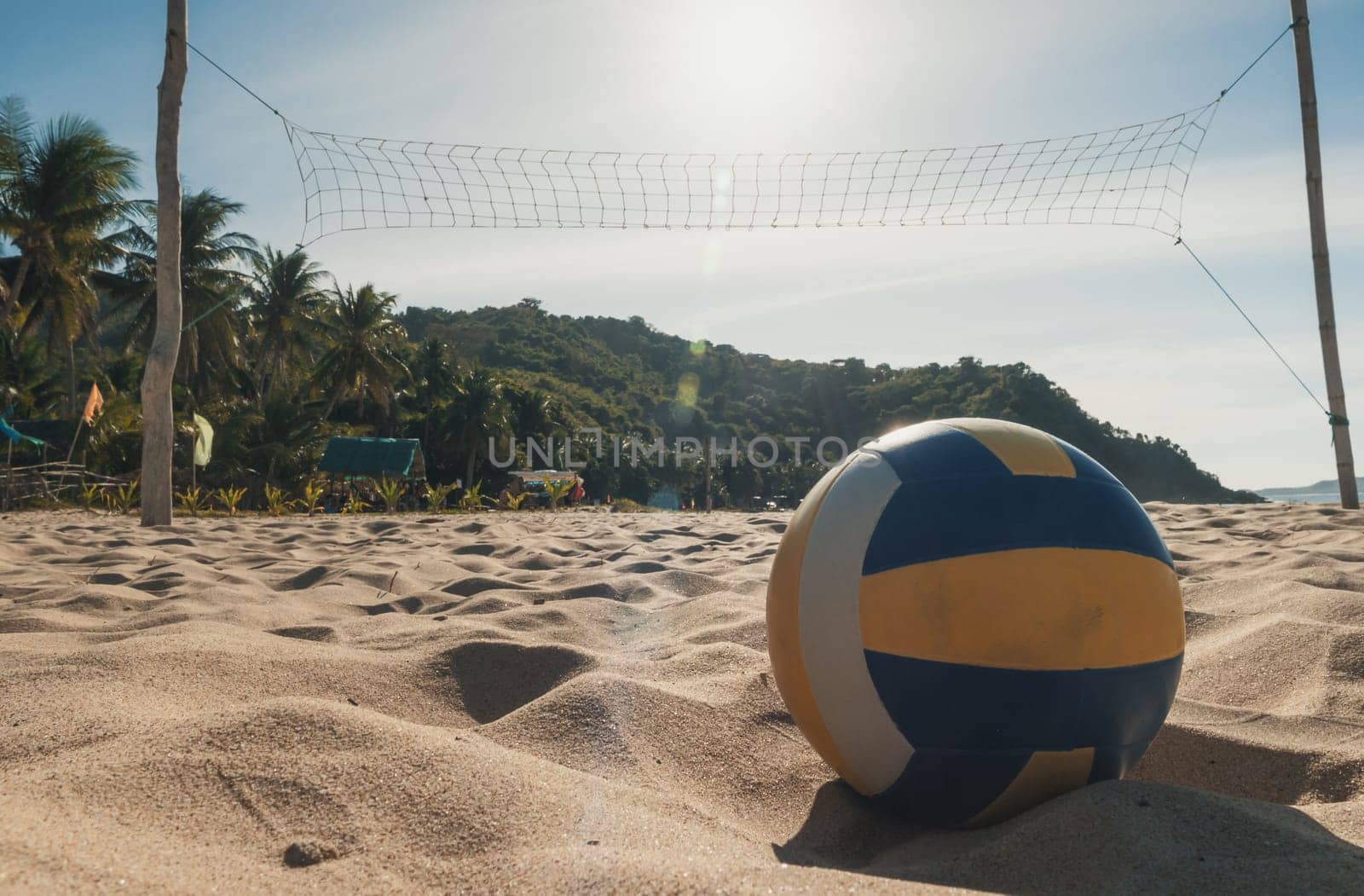 A volleyball rests on the sandy beach beneath a clear, sunny sky. by Busker