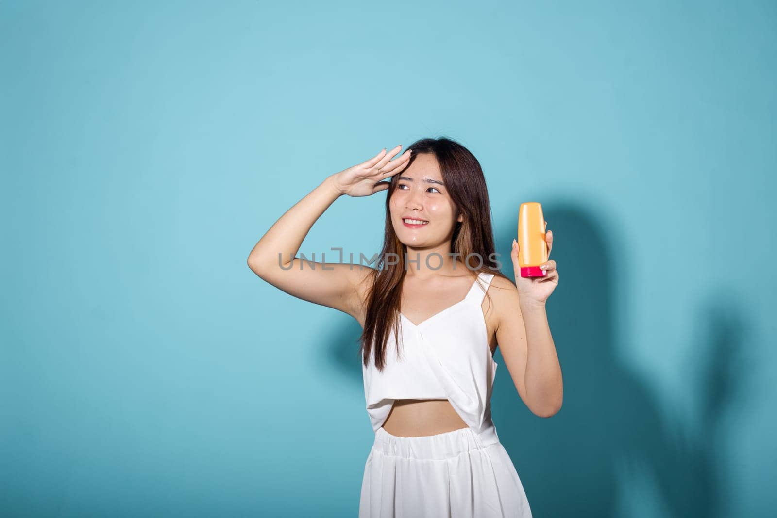 Beautiful Asian young woman holding body lotion on hand by Sorapop