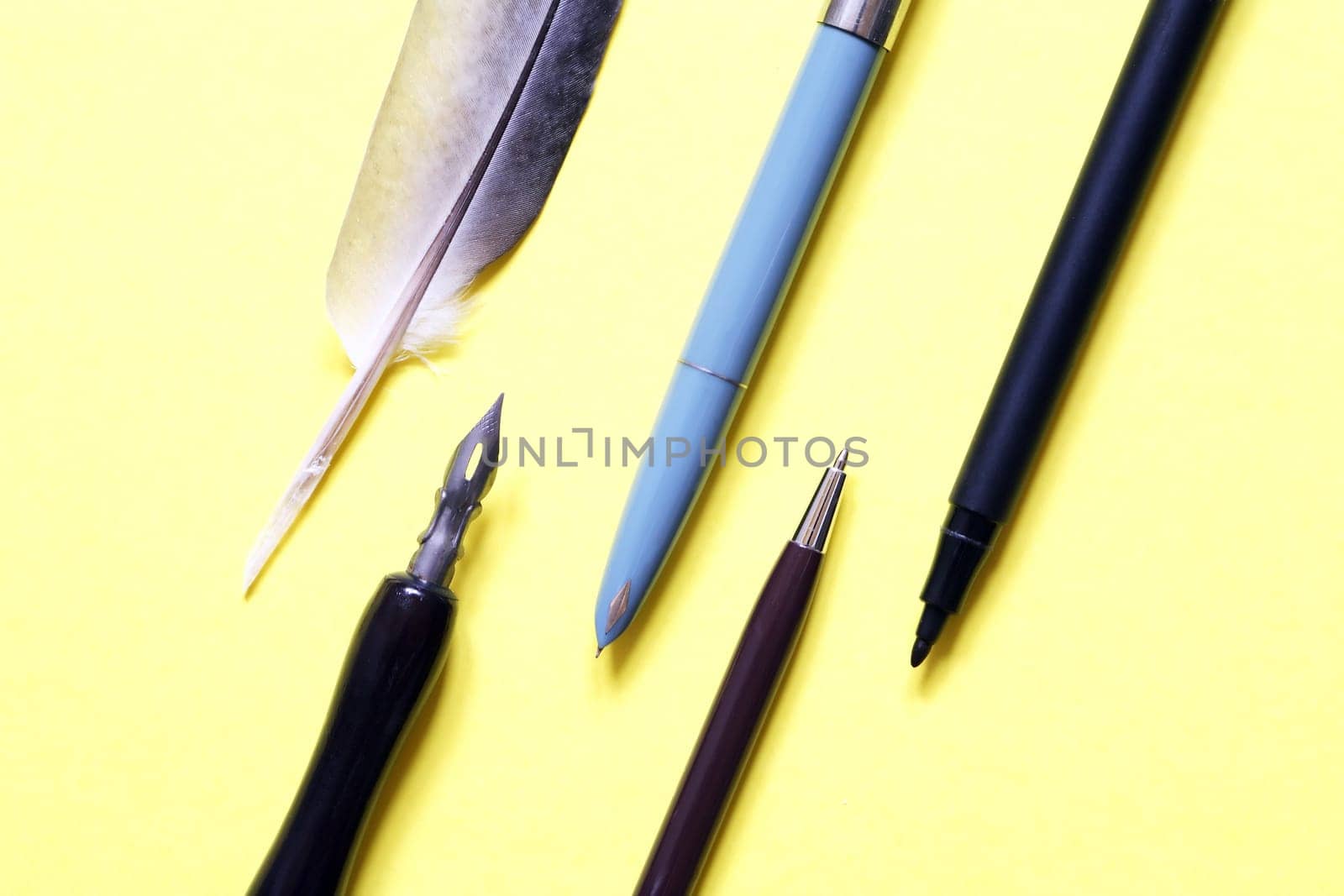 The development of the fountain pen. Set of various pens closeup on yellow paper background