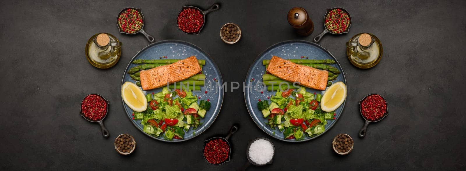 Healthy lunch with grilled trout with asparagus and fresh tomato and cucumber salad, a lemon slice. Food on a blue round plate by ndanko