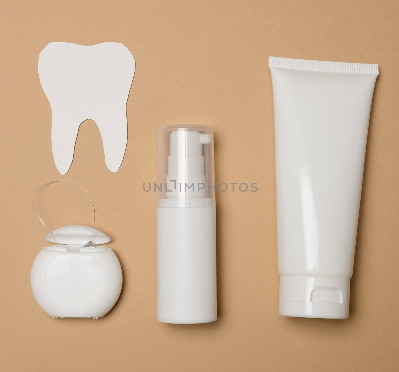 Tube with toothpaste, dental floss  on a brown background, oral hygiene by ndanko