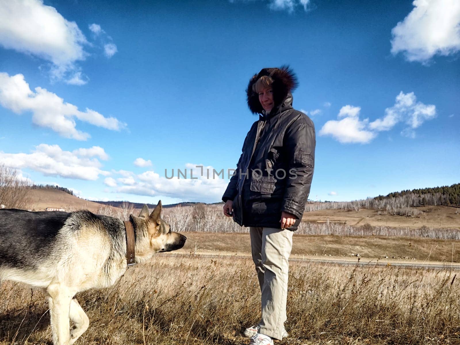 Adult girl or middle aged woman with shepherd dog in an autumn day