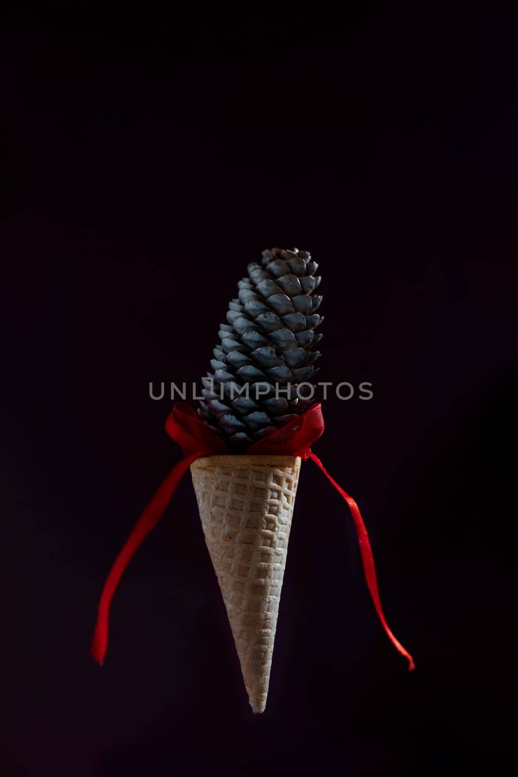 A cone of ice cream is suspended in the air with a red ribbon by Matiunina