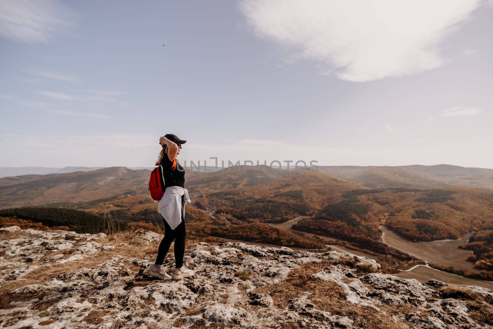 woman on mountain peak looking in beautiful mountain valley in autumn. Landscape with sporty young woman, blu sky in fall. Hiking. Nature.