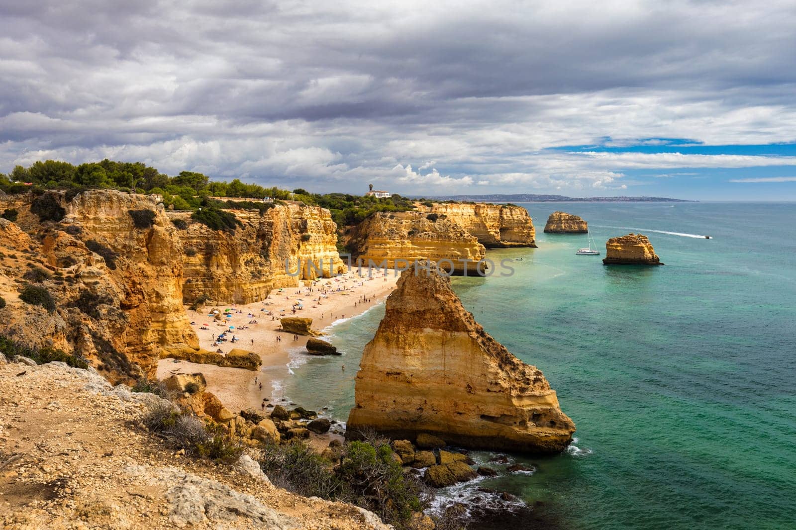 Natural caves at Marinha beach, Algarve Portugal. Rock cliff arches on Marinha beach and turquoise sea water on coast of Portugal in Algarve region.  by DaLiu