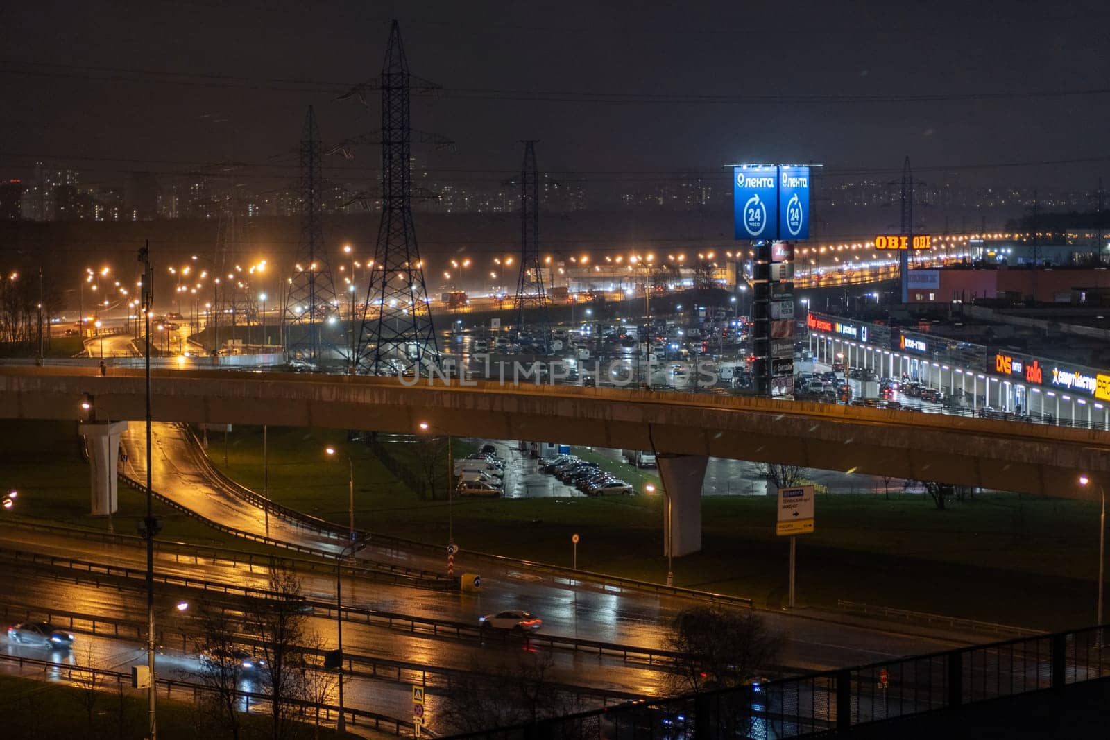 On night roads, cars drive over a bridge and a road junction. Urban cityscape by AnatoliiFoto