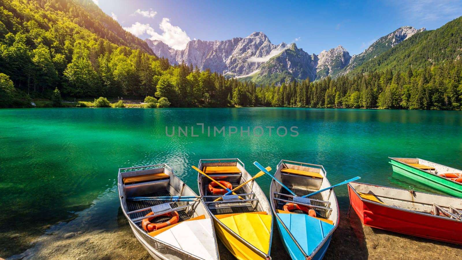 Picturesque lake Lago Fusine with colorful boats. Fusine lake with Mangart peak on background. Popular travel destination of Julian Alps. Location: Tarvisio comune , Province of Udine, Italy, Europe.