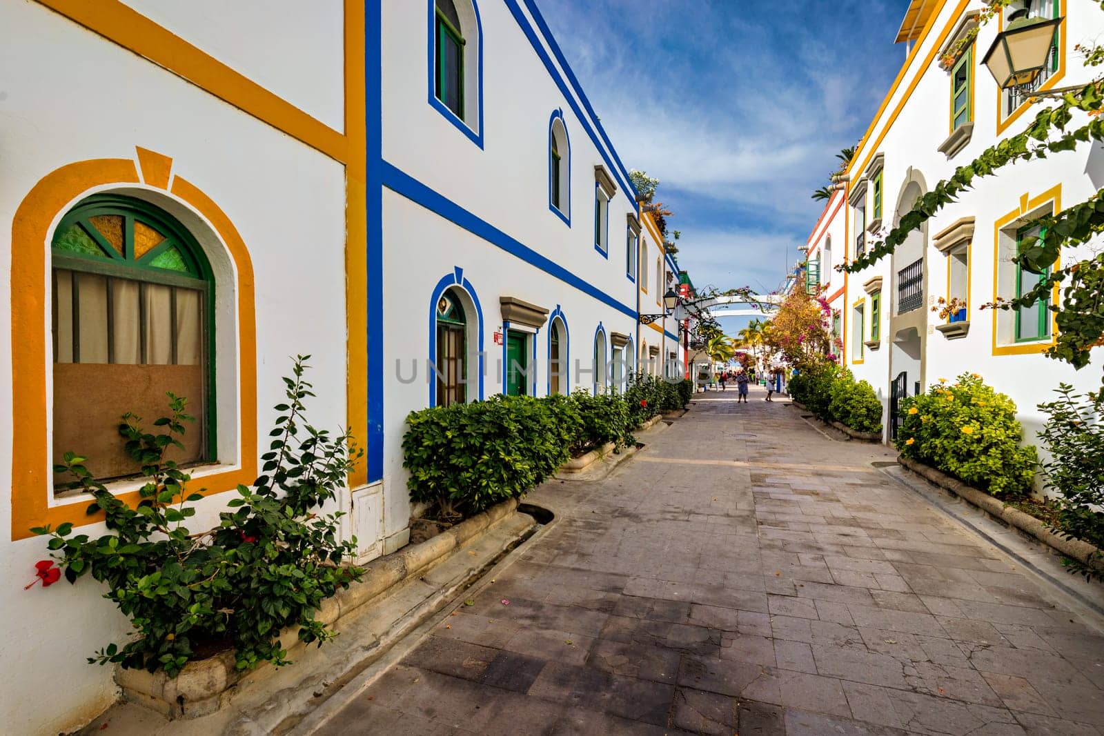 Street with blooming flowers in Puerto de Mogan, Gran Canaria, Spain. Favorite vacation place for tourists and locals on island. Puerto de Mogan with lots of bougainvillea flowers, Canary Island.