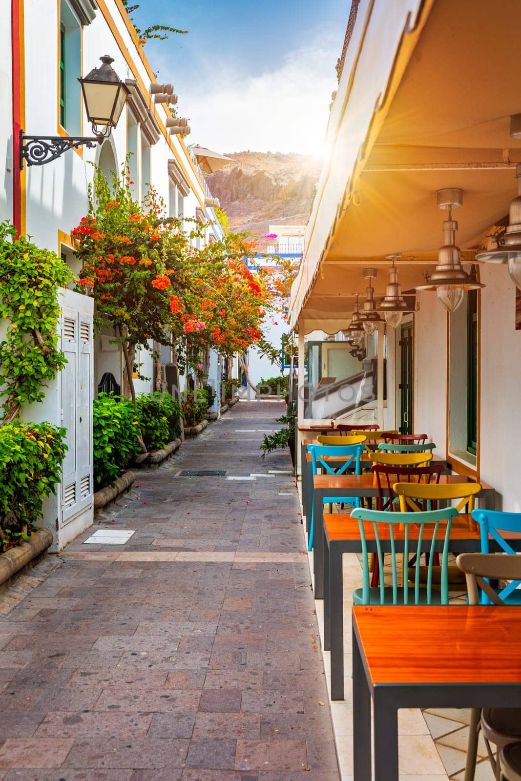 Street with blooming flowers in Puerto de Mogan, Gran Canaria, Spain. Favorite vacation place for tourists and locals on island. Puerto de Mogan with lots of bougainvillea flowers, Canary Island.