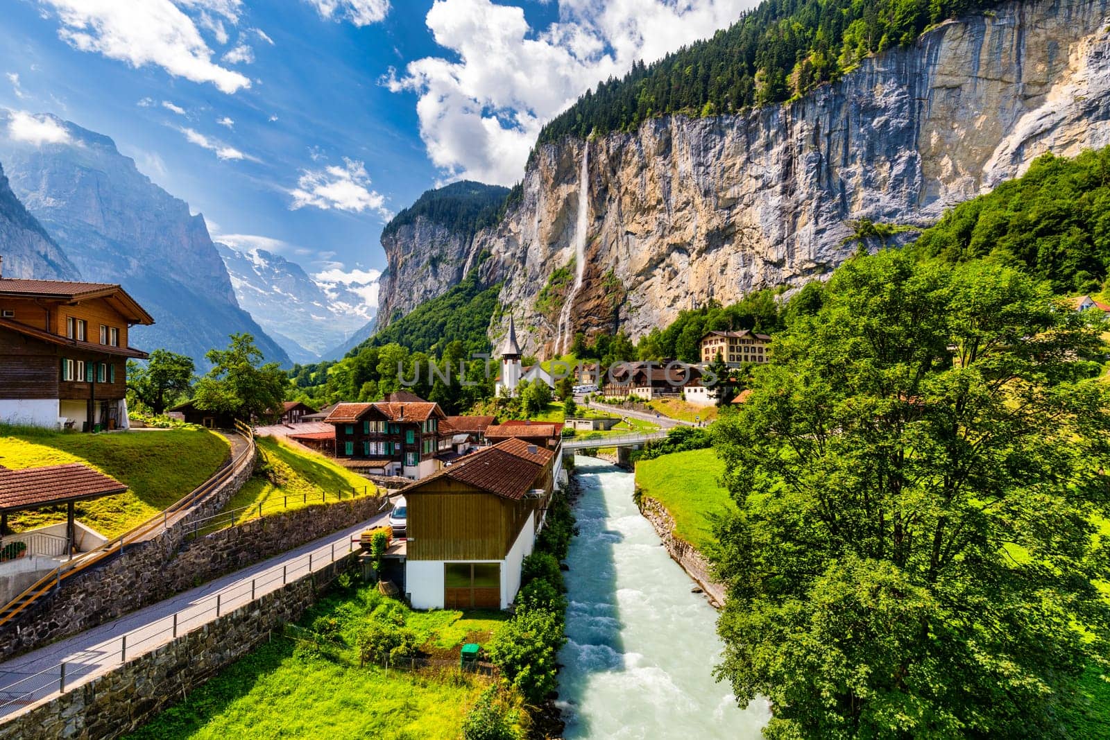 Amazing summer landscape of touristic alpine village Lauterbrunnen with famous church and Staubbach waterfall. Location: Lauterbrunnen village, Berner Oberland, Switzerland, Europe.