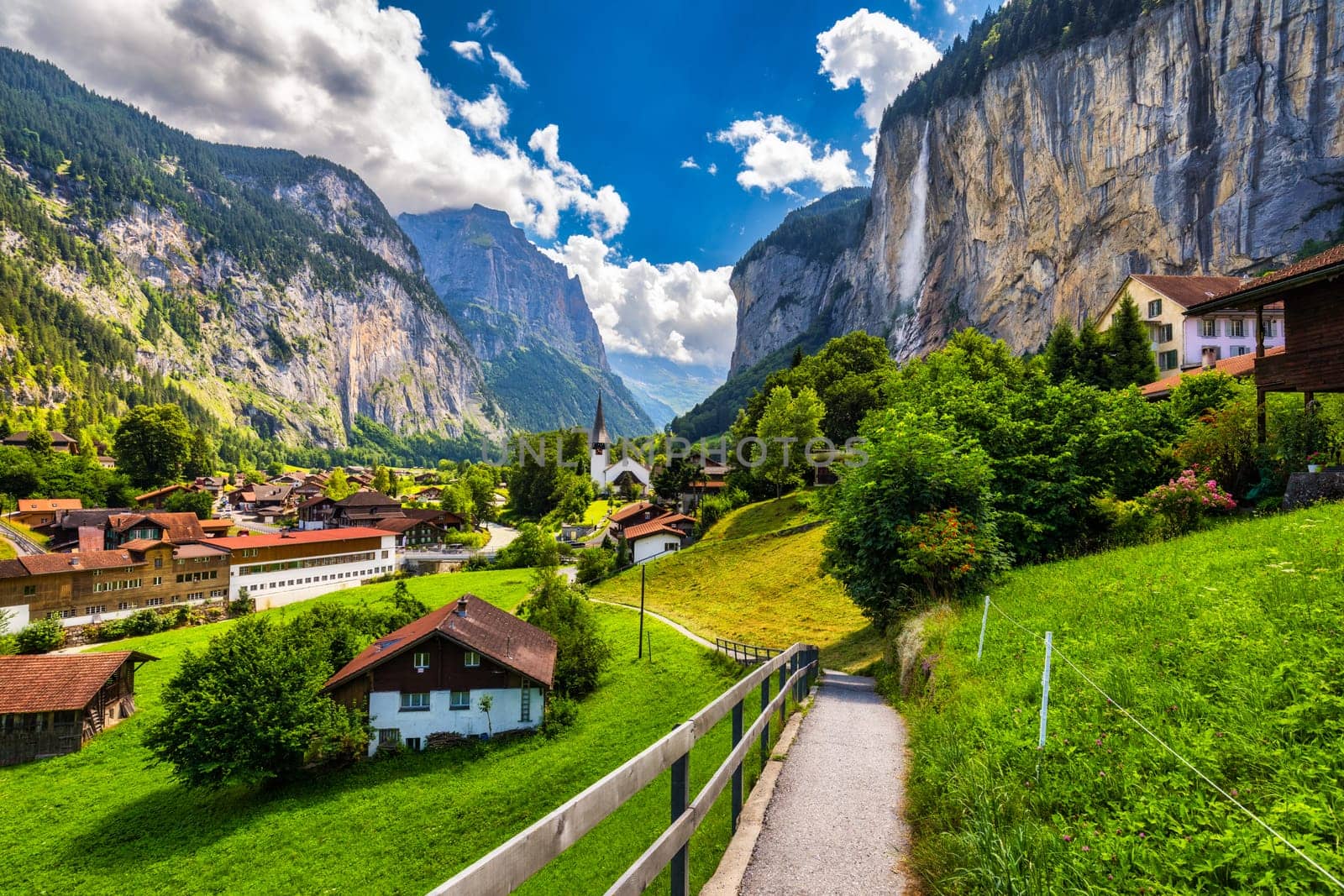 Amazing summer landscape of touristic alpine village Lauterbrunnen with famous church and Staubbach waterfall. Location: Lauterbrunnen village, Berner Oberland, Switzerland, Europe.