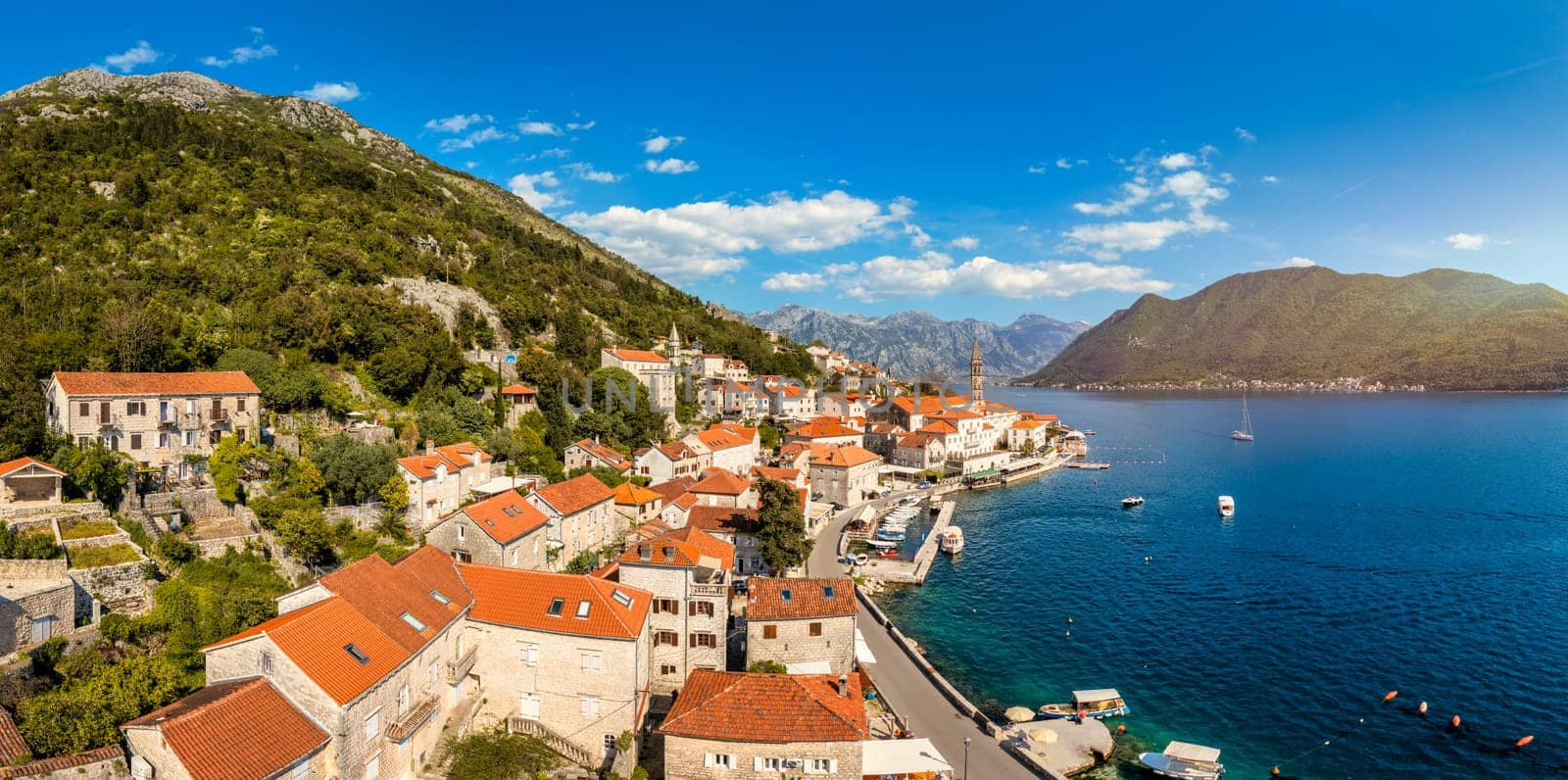 View of the historic town of Perast at famous Bay of Kotor on a beautiful sunny day with blue sky and clouds in summer, Montenegro. Historic city of Perast at Bay of Kotor in summer, Montenegro.