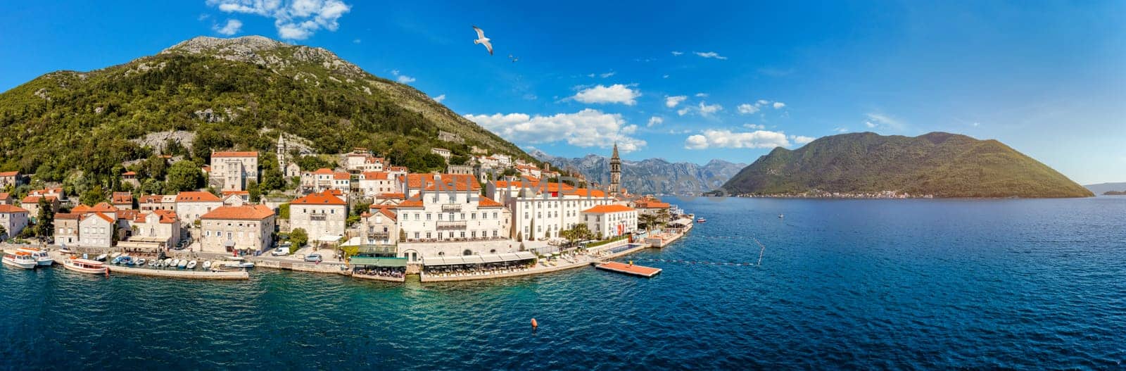 View of the historic town of Perast at famous Bay of Kotor on a beautiful sunny day with blue sky and clouds in summer, Montenegro. Historic city of Perast at Bay of Kotor in summer, Montenegro.