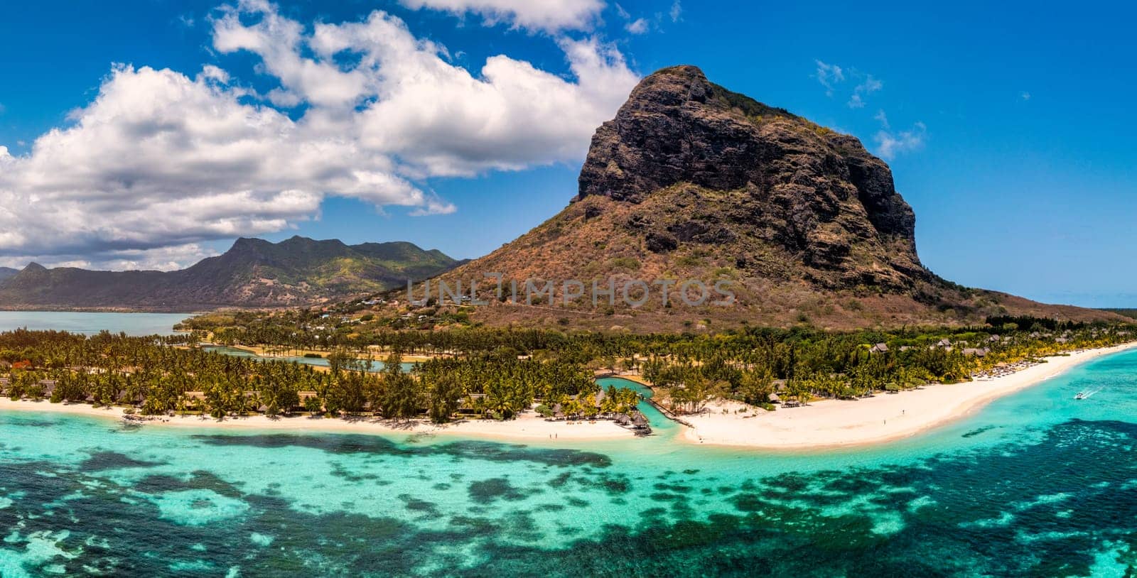 Beach with palm trees and umbrellas on Le morne beach in Mauriutius. Luxury tropical beach and Le Morne mountain in Mauritius. Le Morne beach with palm trees, white sand and luxury resorts, Mauritius