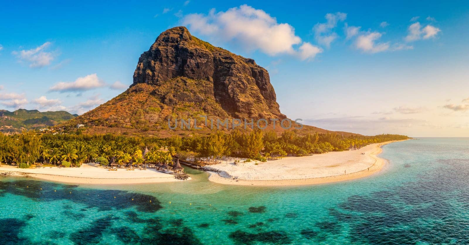 Beach with palm trees and umbrellas on Le morne beach in Mauriutius. Luxury tropical beach and Le Morne mountain in Mauritius. Le Morne beach with palm trees, white sand and luxury resorts, Mauritius