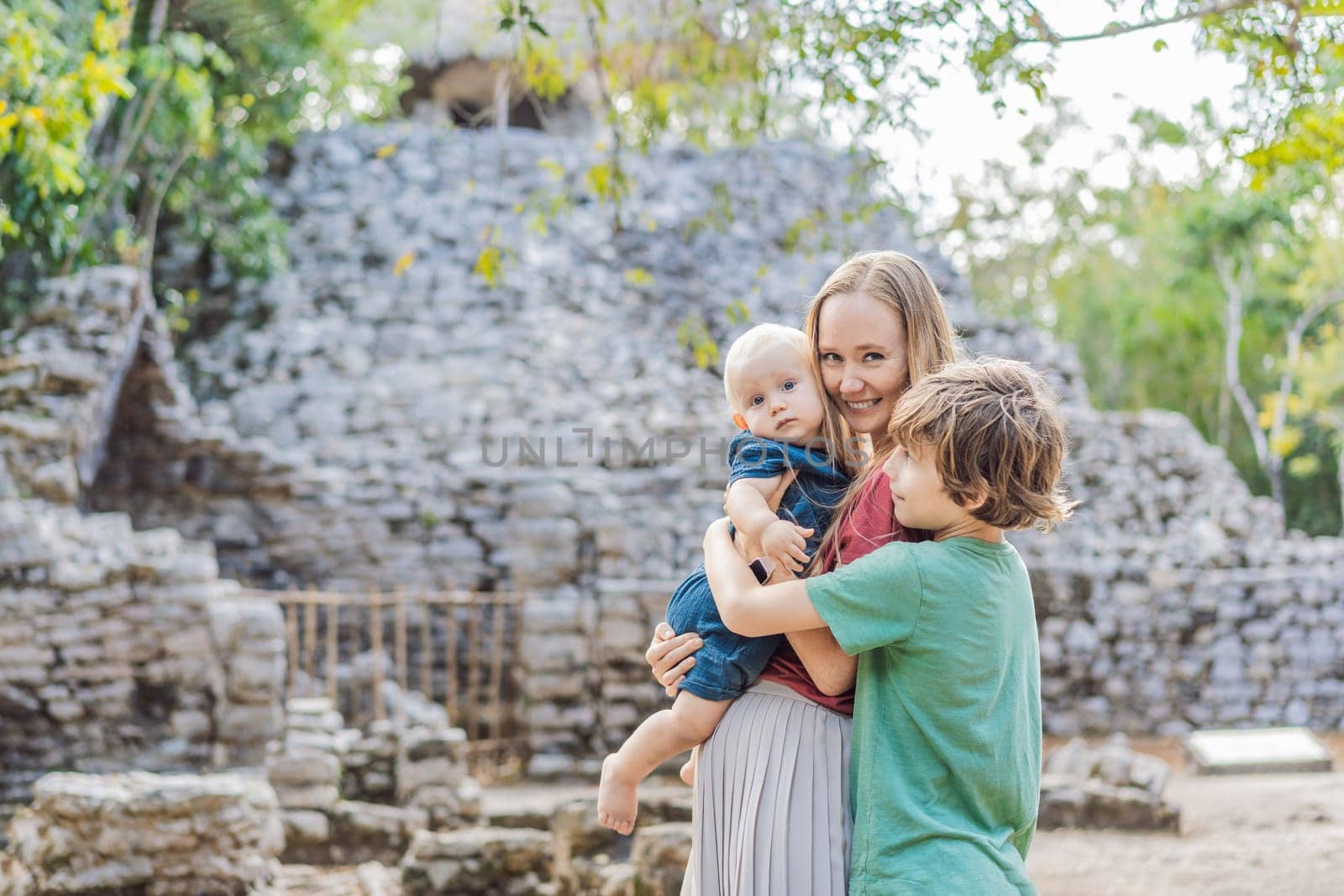 Mom and two sons tourists at Coba, Mexico. Ancient mayan city in Mexico. Coba is an archaeological area and a famous landmark of Yucatan Peninsula. Cloudy sky over a pyramid in Mexico.