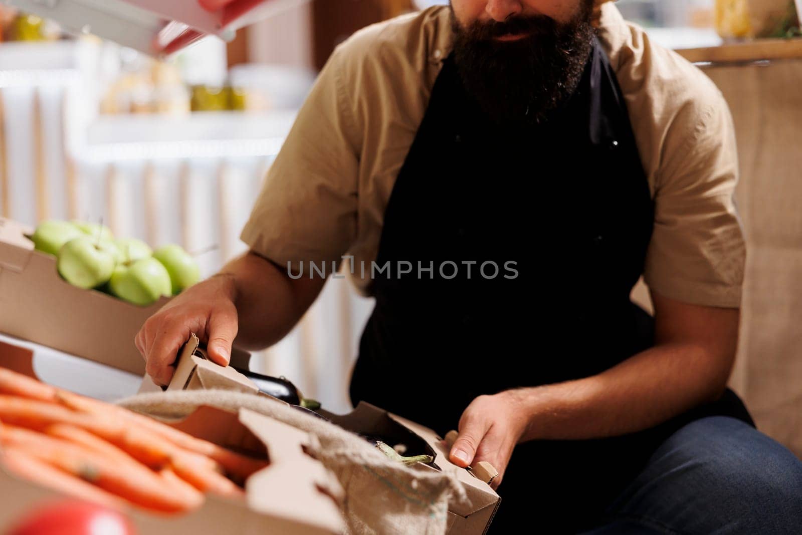 Green living merchant adding crates full of vegetables from his own garden on zero waste shop shelves. Storekeeper restocking local neighborhood store with natural additives free food items